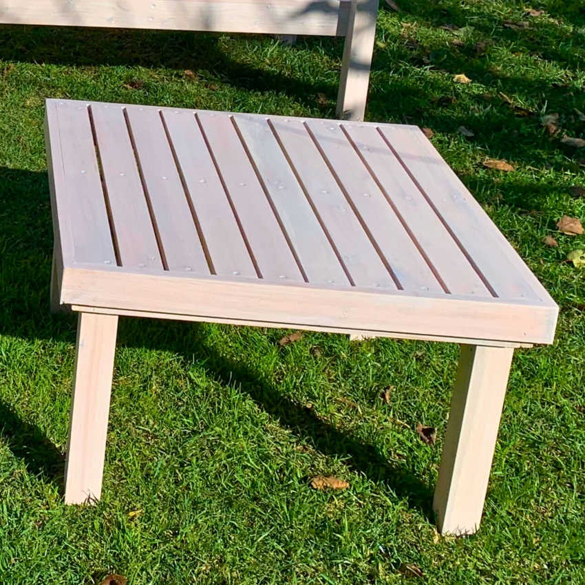 Mesa baja de madera blanca sobre el césped