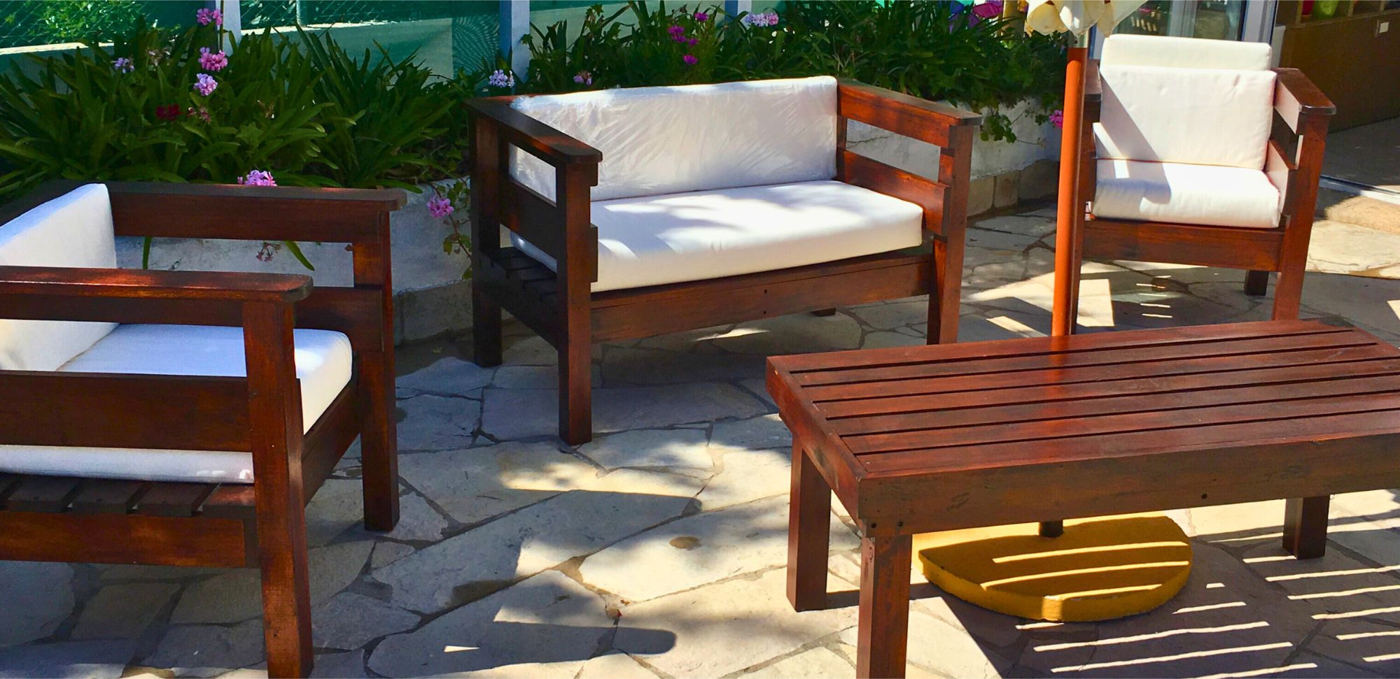 Living de exterior de madera en un patio con plantas