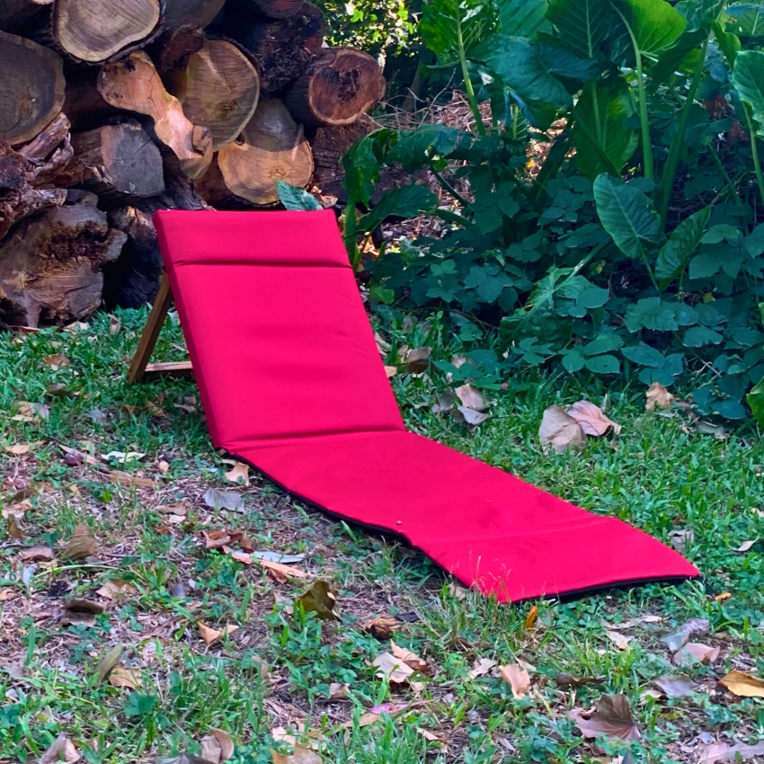 Reposera baja con colchoneta roja sobre el césped
