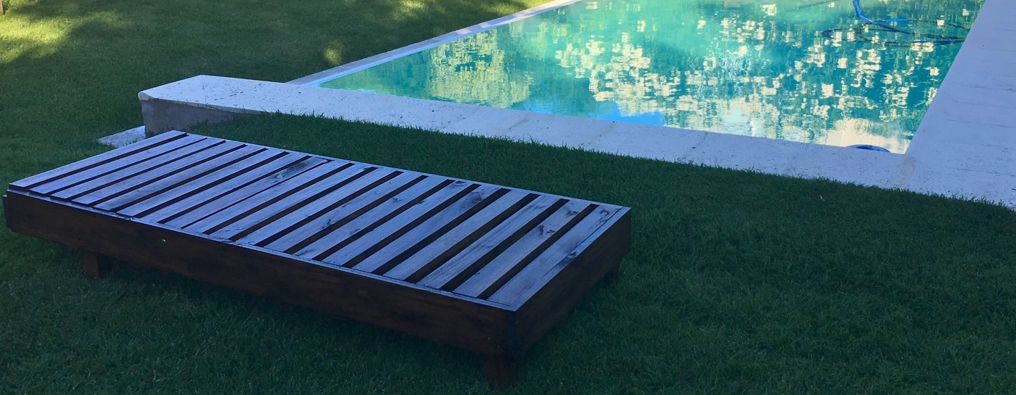 Camastro de madera bajo junto a una pileta